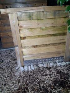 Image qui représente un composteur dans un jardin avec des plaques en métal en partie basse pour éviter l'introduction des rongueurs posé par l"entreprise FRAIDE SERVICES.
